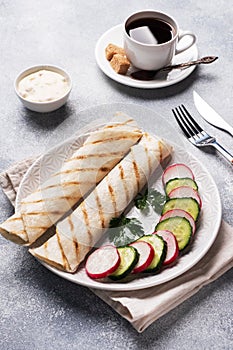 Roll with cheese and herbs. Grilled pita bread with filling. Cucumber radish salad. The concept of a healthy Breakfast. Cup of