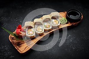 Roll Ebi Ringo with tiger shrimp, cream cheese, apple and tobiko, on a wooden board, on a dark background