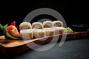 Roll Ebi Ringo with tiger shrimp, cream cheese, apple and tobiko, on a wooden board, on a dark background