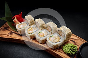 Roll Ebi Ringo with tiger shrimp, cream cheese, apple and tobiko, on a wooden board, on a dark background