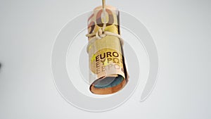 Roll of European cash banknotes tied with an elastic band swinging