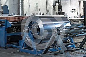 Roll of galvanized steel sheet at cutting machine, ironworks and metalwork manufacturing factory, production metal pipes and tubes