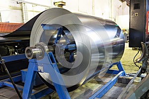 Roll of galvanized steel sheet at cutting machine, ironworks and metalwork manufacturing factory, production metal pipes and tubes photo