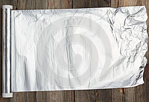 Roll of gray foil for baking and packaging food on a wooden background