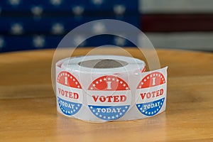 Roll of I Voted Today paper stickers on table with US Flag in background