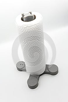 Roll of kitchen paper towel standing on grey plastic holder