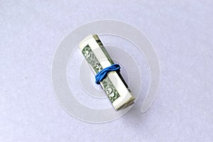 A roll of money dollars with an elastic band on a white background