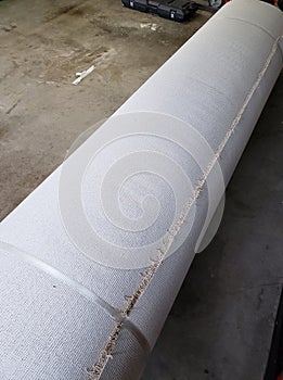 A roll of new carpet in the garage of house for replace