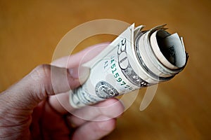 Roll of paper banknotes (American Dollars, USD) hold by a male hand