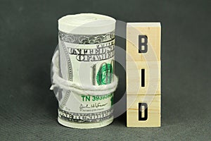 a roll of paper money and a wooden cube with the word bid