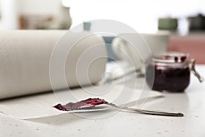 Roll of paper towels and spoon with jam on white table