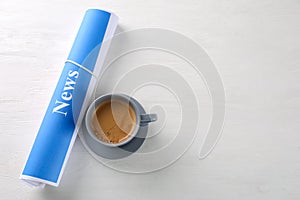 Roll of papers with word NEWS and cup of coffee on wooden table