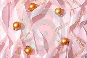 Roll pink gold ribbons and golden balls on pink background. Cosmetics product advertising backdrop. Copy space, Christmas flat lay