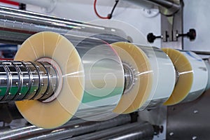 Roll of plastic packaging film on the automatic packing machine in food product factory. industrial and technology concept