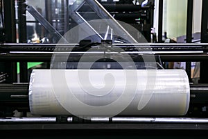 Roll of plastic packaging film on the automatic packing machine in food product factory. industrial and technology concept