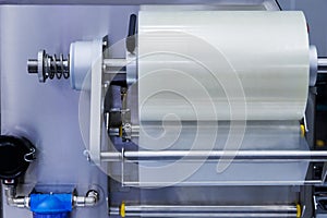 roll of plastic packaging film on the automatic packing machine in food product factory. industrial and technology concept