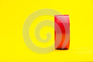 A roll of red duct tape isolated on a yellow background