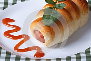 Roll with sausage on a plate close-up horizontal view from above