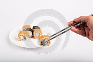Roll of sushi on a plate, Sushi roll on a tablet, white background, Sushi roll and hand with chopsticks