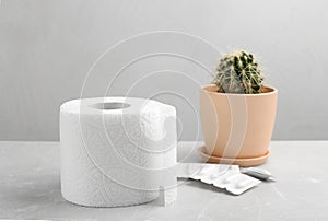 Roll of toilet paper, suppositories and cactus. Hemorrhoid problems