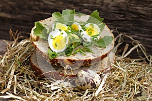 Roll topped with boiled quail eggs in hay