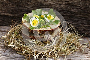 Roll topped with boiled quail eggs in hay