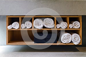 Roll white soft towels in built in wooden shelf