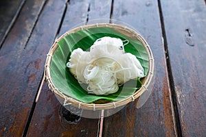 Roll white thai rice noodle on the banana leaf in the bamboo basket. Thai food (Thai language Kanom jeen)