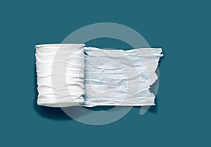 Roll of white toilet paper on a dark blue green background with empty space.