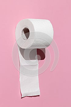 Roll of a white toilet paper isolated on a pink background close-up. hard shadows from the sun at noon