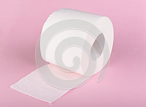 A roll of white toilet paper isolated on a pink background. The paper product used in the sanitary and hygienic purposes
