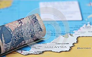 Rolled banknote money one ringgit Malaysia put on the Malaysian map. Concept of currency or travel
