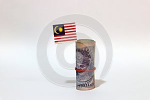 Rolled banknote money one ringgit Malaysia and stick with mini Malaysian flag on white background