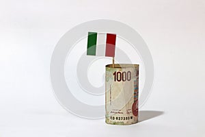 Rolled banknote money one thousand Lire Italy and stick with mini Italia nation flag on white background