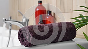 Rolled bath towel on tub in bathroom