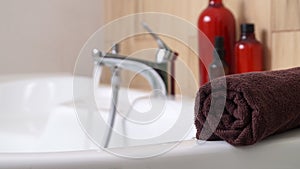 Rolled bath towel on tub in bathroom, space for text