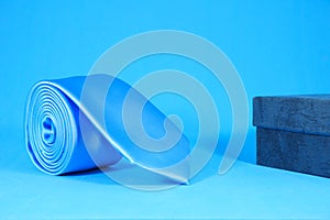 Rolled blue tie isolated on blue background close-up view