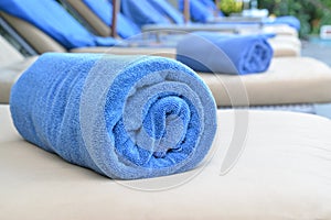 Rolled blue towel on sun lounges.