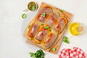 Rolled buns with basil pesto on a wooden board on a light concrete background. Unsweetened pastries, snack buns