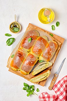 Rolled buns with basil pesto on a wooden board on a light concrete background. Unsweetened pastries, snack buns