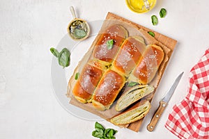 Rolled buns with basil pesto on a wooden board on a light concrete background. Unsweetened pastries, snack buns