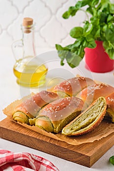 Rolled buns with basil pesto on a wooden board on a light concrete background. Unsweetened pastries, snack buns