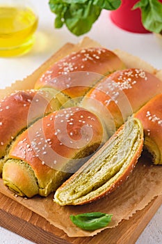 Rolled buns with basil pesto on a wooden board on a light concrete background. Unsweetened pastries, snack buns