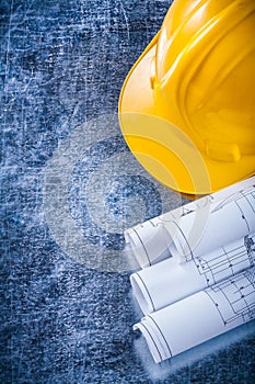 Rolled construction plans and yellow hard hat on