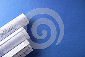 Rolled engineering drawings at blue background with copy space