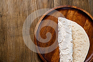 rolled flatbread pita on a round wooden cutting board. bakery. flat bread