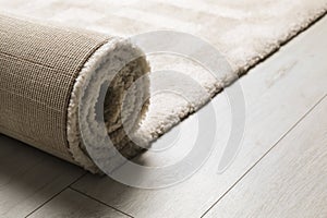 Rolled fuzzy carpet on wooden background.