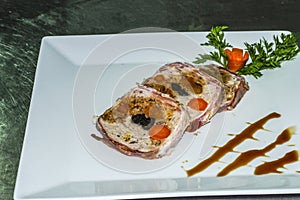 Rolled meatloaf with sauce, presented in slices on a white plate. photo