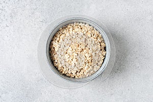 Rolled oats in bowl on grey concrete background