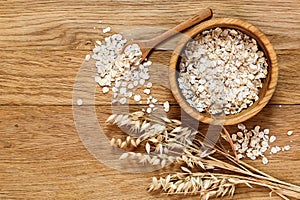 Rolled oats and oat ears of grain on a wooden table photo